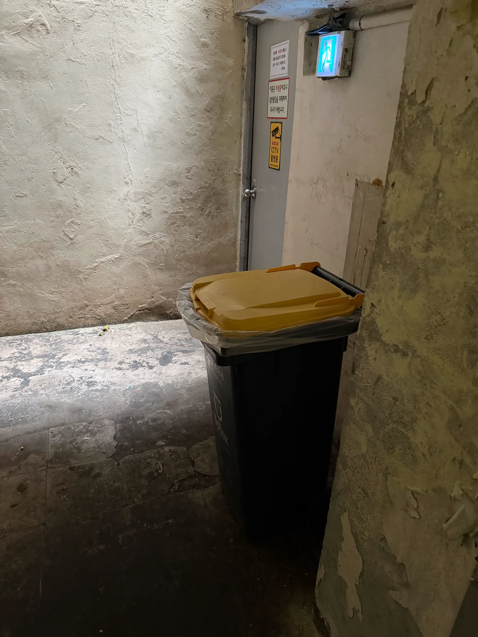 Black food-waste bin with a yellow lid inside the small side door